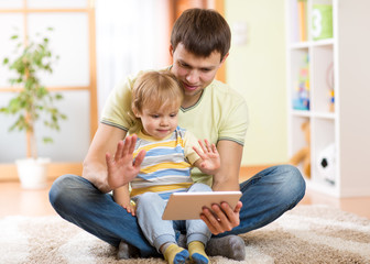 daddy and son kid playing with tablet computer indoors