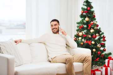 Obraz premium man calling on smartphone at home for christmas