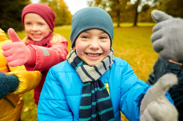 happy children showing thumbs up in autumn park