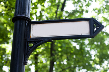 Signpost on a black cast iron column. Retro pointer arrow, vintage design signboard