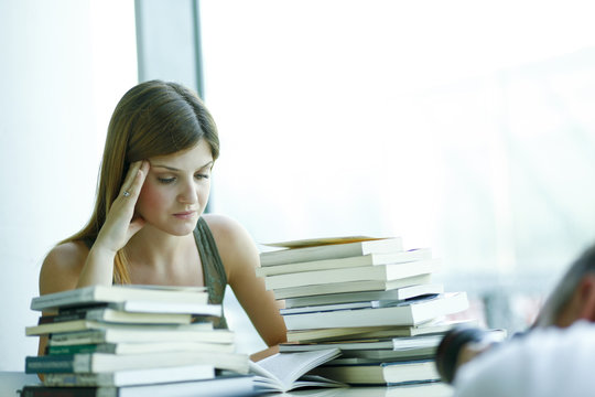 Giovane studentessa prepara una esame in biblioteca