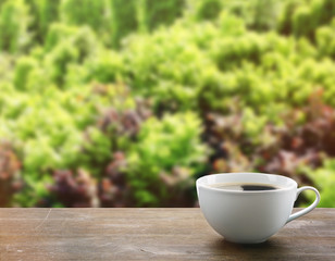 Cup of coffee on table on nature background