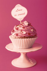 Delicious cupcake with inscription on pink background