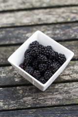 Blackberries in a square bowl on the garden table.