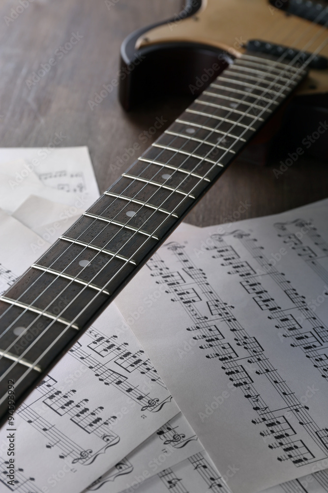 Sticker Electric guitar with music notes on wooden table close up