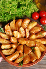 Baked potato wedges on wooden table, top view