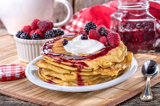 Pancakes with cream, raspberries and blackberries on the table