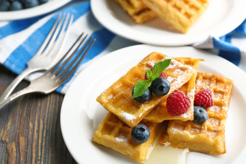 Sweet homemade waffles with forest berries and sauce on table background