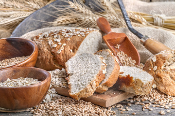 Bread from rye and healthy grains on an old rustic table with a sickle in the background