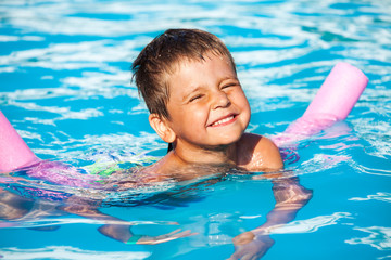 Fototapeta na wymiar Close-up of boy learning to swim with pool noodle
