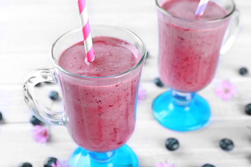 Glasses of blueberry smoothie on wooden table, closeup