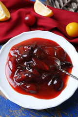 Tasty homemade plum jam in white plate on wooden table, closeup