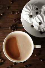Cup of coffee with zephyr and grains on wooden table, top view