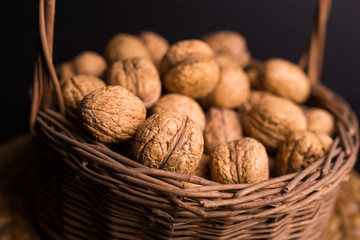 wicker basket with walnuts on a black background