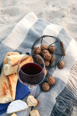 Beautiful romantic composition of red wine, bread and nuts on sandy beach