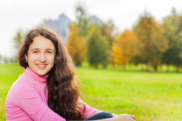 Beautiful girl close-up view sits on green grass