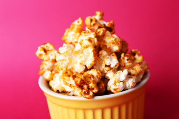 Sweet caramel popcorn on pink background