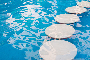 Blue pool with round decorative stones in summer