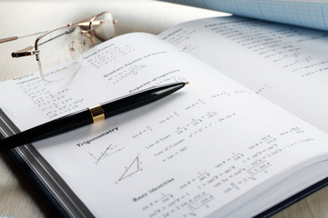School supplies and textbook on mathematics close up