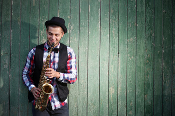 Handsome man plays saxophone on green wooden background