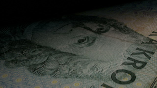 An extreme closeup of swedish kronor banknotes flipping through in a counting machine