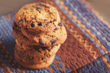 Cookies with chocolate crumbs on ornament napkin against blurred background, close up