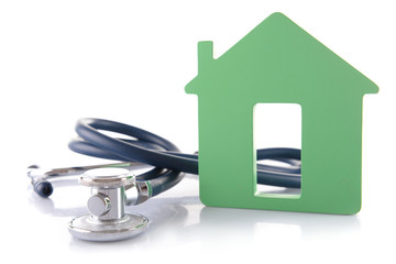 Concept of family medicine - green house and stethoscope isolated on white background