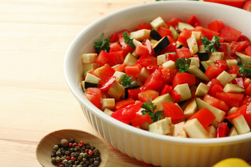 Ratatouille before cooking and ingredients, on wooden background