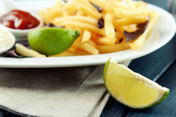 French fried potatoes with sauce and lime on white tray