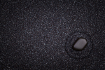 A black  zen stone with circle patterns in the black grain sand