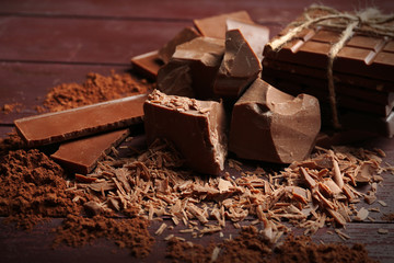 Black chocolate pieces with spices on wooden background