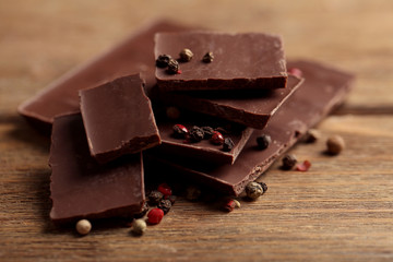Black chocolate pieces with pepper on wooden background