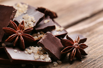 Black chocolate pieces with spices on wooden background