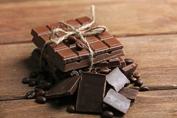 Milk chocolate pieces and coffee grains on wooden background