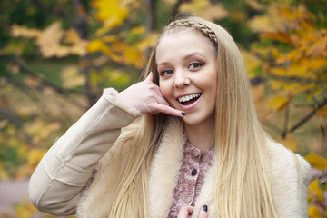 Beautiful happy blonde woman making a call me gesture