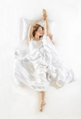 Dancing ballet dreamer dressed in white with white sheets, studio shot on white background. Expressive woman in action, dreaming concept. Dreaming of becoming professional dancer.