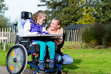 Disability/ A disabled child in a wheelchair with a carer going for a walk