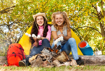 Two girls roasting smores near fireplace