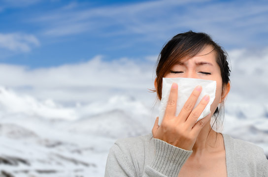 Asian woman catch a cold with snow background.