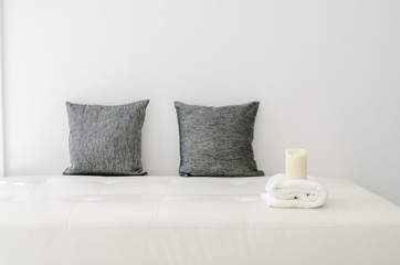 Fototapeta na wymiar Black decorative pillows , candle and white towel on a white cas