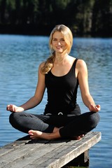 Fototapeta na wymiar Junge Frau macht Yoga an einem See