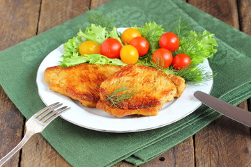 juicy grilled pork chop with greens and tomatoes