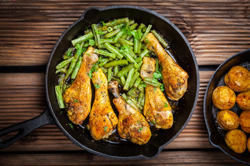 Chicken legs in pan with potatoes and salad