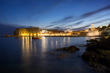 Lit Old Town and rocky coast in Dubrovnik, Croatia at night.