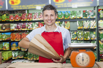 smiling seller of seeds for gardeners in his shop