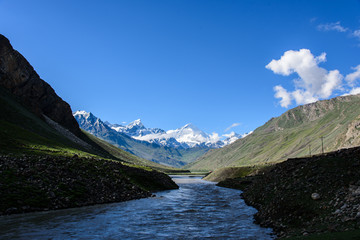Naklejka na ściany i meble River with sunlight and shade and snow mountain background, Kash