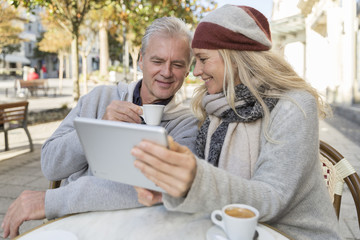 mature couple using a digital tablet at a bar terrace