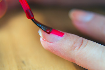 Painting fingernails with red nail polish.
