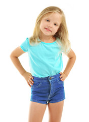 Fototapeta premium Happy young blonde girl in blue t-shirt and denim shorts posing with hands on hips, childhood innocence and playful expression