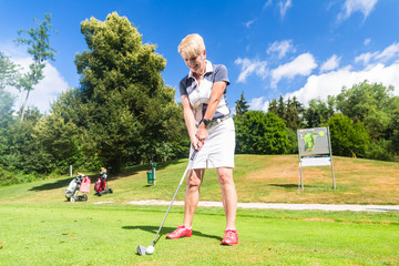 Senior Frau beim Golf macht Abschlag